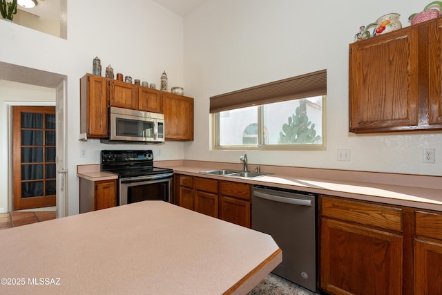 kitchen with appliances with stainless steel finishes, sink, and a towering ceiling