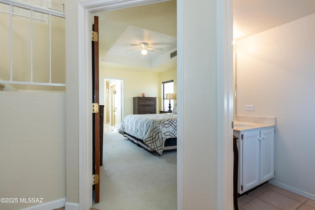 bedroom featuring sink, light colored carpet, and a raised ceiling