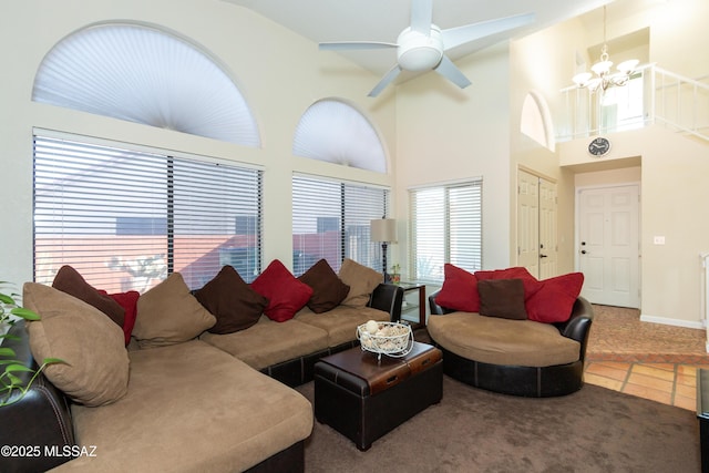 living room featuring tile patterned floors, ceiling fan with notable chandelier, and a high ceiling