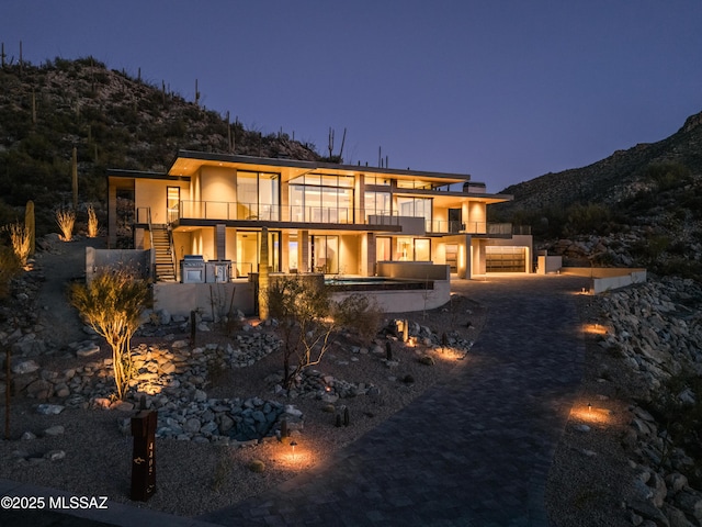 back house at dusk with a balcony, a garage, and a mountain view