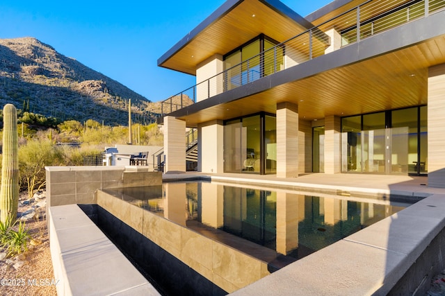 rear view of house featuring a mountain view and a patio area