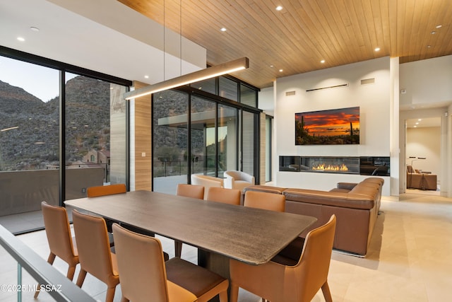 dining room featuring wooden ceiling, expansive windows, and a high ceiling