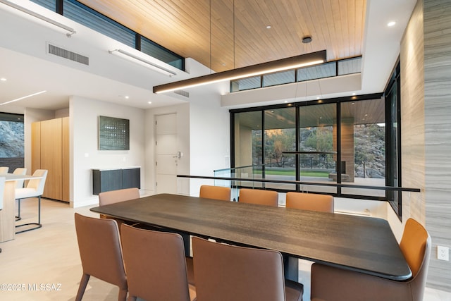 dining room featuring wood ceiling and a towering ceiling