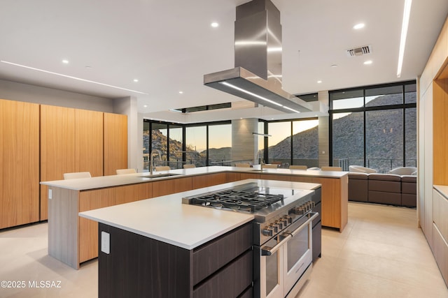 kitchen featuring sink, a center island, island range hood, expansive windows, and range with two ovens