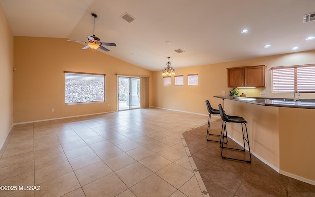 kitchen with sink, light tile patterned floors, a breakfast bar, ceiling fan with notable chandelier, and vaulted ceiling