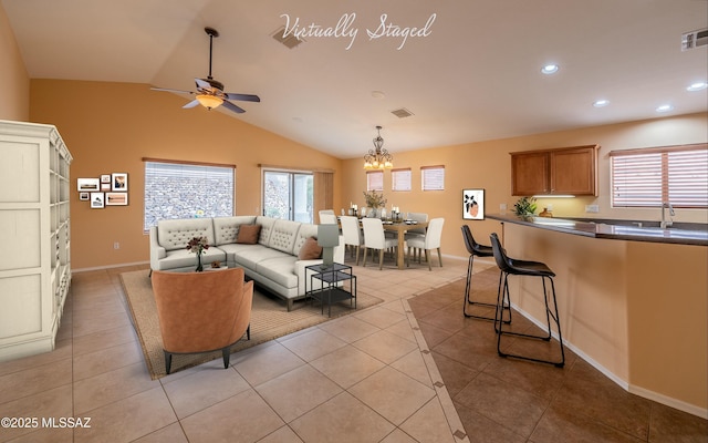 living room featuring vaulted ceiling, ceiling fan with notable chandelier, sink, and light tile patterned floors