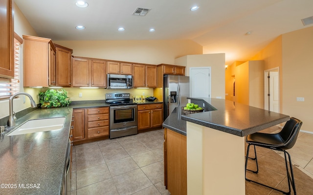 kitchen featuring sink, light tile patterned floors, a breakfast bar, stainless steel appliances, and a kitchen island