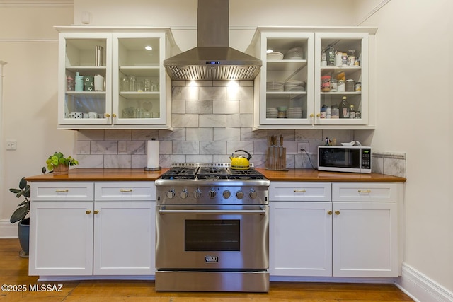 kitchen featuring wooden counters, white cabinetry, stainless steel range, island exhaust hood, and decorative backsplash