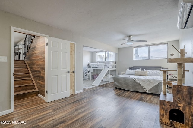 bedroom with a wall mounted air conditioner, dark hardwood / wood-style floors, and ceiling fan