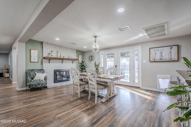 dining space with dark wood-type flooring, a fireplace, and french doors