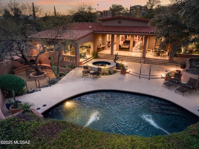 pool at dusk featuring a patio, an in ground hot tub, and central air condition unit