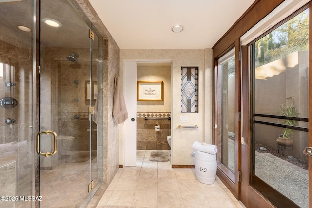 bathroom featuring tile patterned flooring, tile walls, an enclosed shower, and toilet