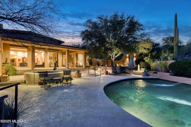 pool at dusk featuring a patio