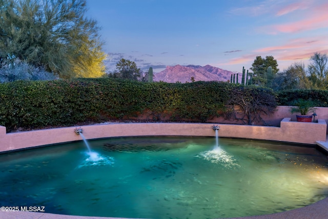 pool at dusk featuring a mountain view