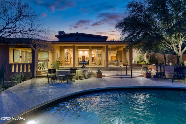 back house at dusk with a patio