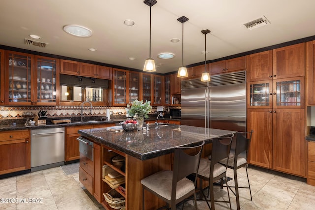 kitchen featuring pendant lighting, sink, a breakfast bar area, a kitchen island with sink, and stainless steel appliances