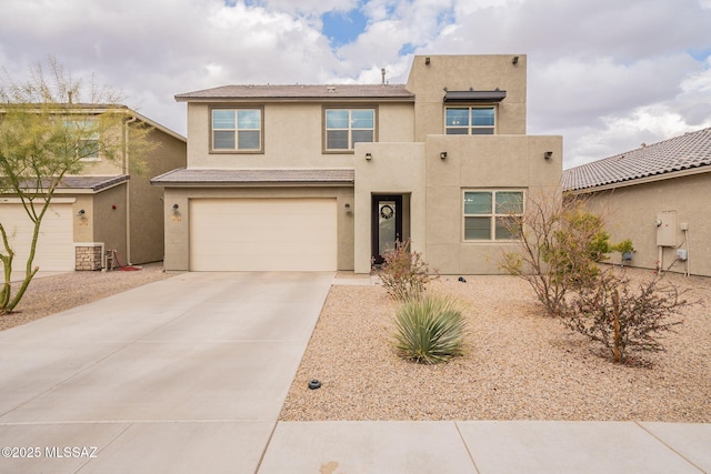 adobe home featuring an attached garage, concrete driveway, and stucco siding