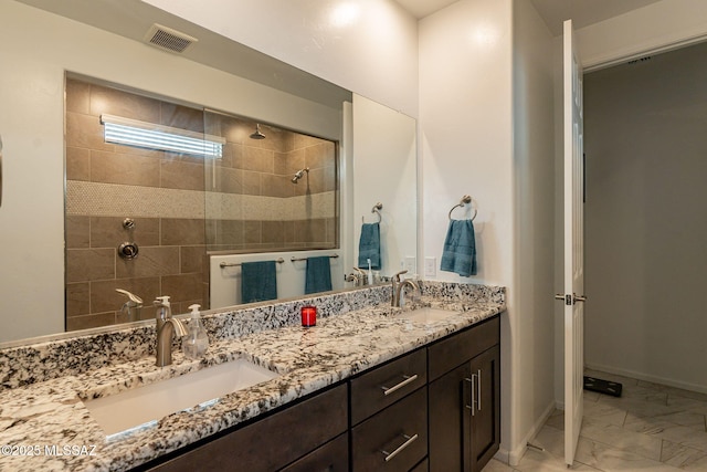 bathroom featuring tiled shower and vanity