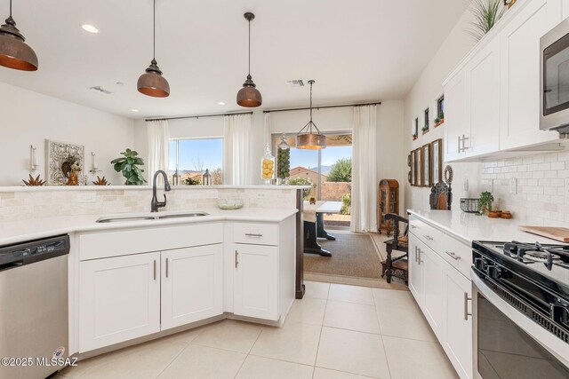 kitchen featuring sink, white cabinetry, light tile patterned floors, appliances with stainless steel finishes, and pendant lighting