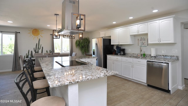 kitchen with pendant lighting, appliances with stainless steel finishes, white cabinetry, a center island, and island range hood