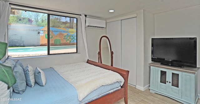 bedroom featuring multiple windows, light wood-type flooring, a wall unit AC, and a closet