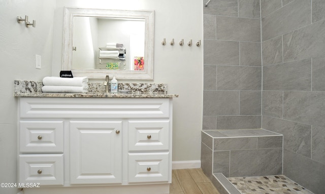 bathroom featuring hardwood / wood-style flooring, vanity, and a tile shower