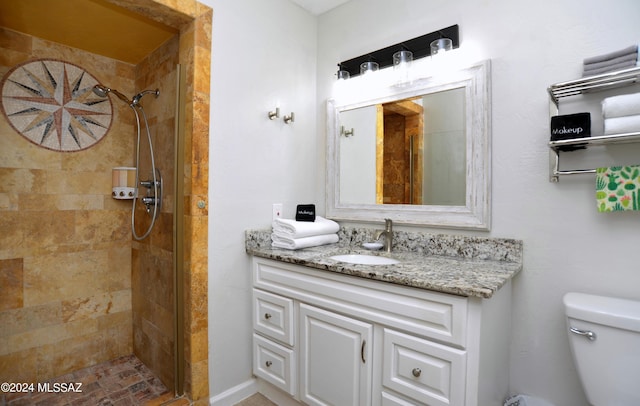 bathroom with vanity, toilet, and a tile shower