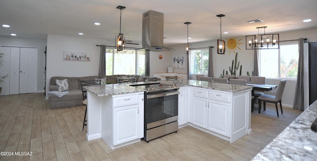 kitchen with stainless steel range with electric cooktop, white cabinetry, a wealth of natural light, pendant lighting, and island exhaust hood