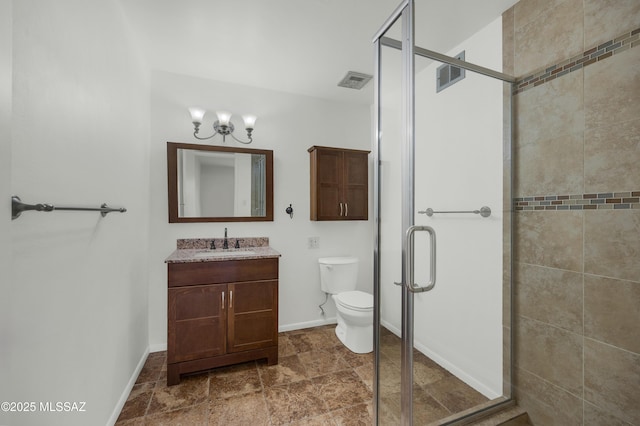 bathroom with vanity, a notable chandelier, a shower with shower door, and toilet