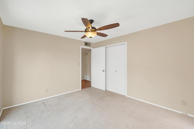 unfurnished bedroom with ceiling fan, light colored carpet, and a closet