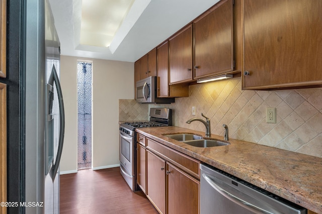 kitchen featuring dark hardwood / wood-style floors, tasteful backsplash, a raised ceiling, sink, and stainless steel appliances