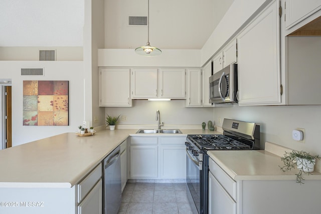 kitchen with decorative light fixtures, sink, white cabinets, light tile patterned floors, and stainless steel appliances