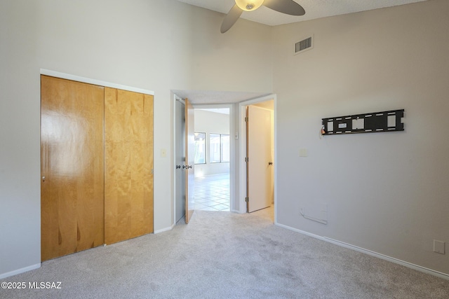 unfurnished bedroom featuring high vaulted ceiling, light colored carpet, a closet, and ceiling fan