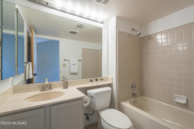 full bathroom featuring vanity, tiled shower / bath, toilet, and a textured ceiling