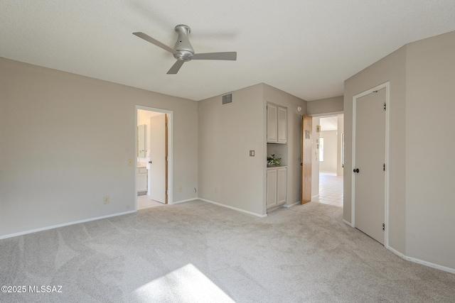 unfurnished bedroom with ceiling fan, light colored carpet, and ensuite bath