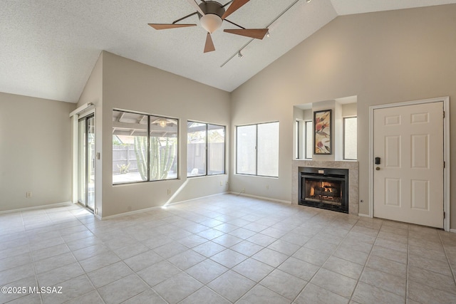 unfurnished living room featuring a tile fireplace, ceiling fan, high vaulted ceiling, a textured ceiling, and light tile patterned flooring