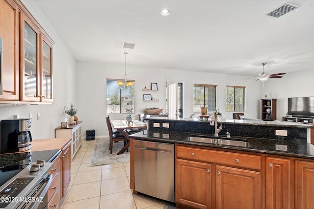 kitchen with sink, appliances with stainless steel finishes, dark stone countertops, plenty of natural light, and decorative light fixtures