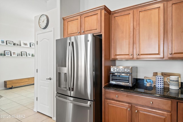 kitchen featuring dark stone countertops, light tile patterned floors, and stainless steel refrigerator with ice dispenser