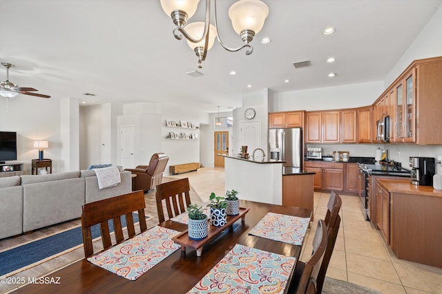 dining space featuring light tile patterned flooring and ceiling fan with notable chandelier