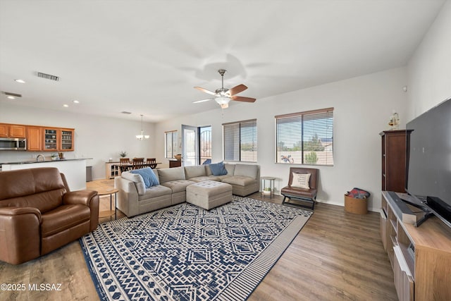 living room with wood-type flooring and ceiling fan with notable chandelier