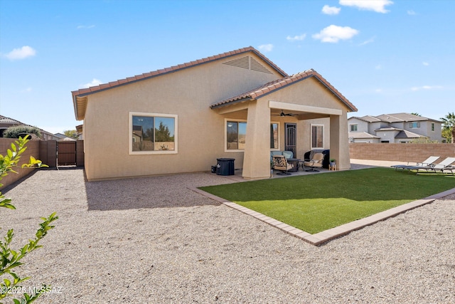 rear view of house with a patio, ceiling fan, and a lawn