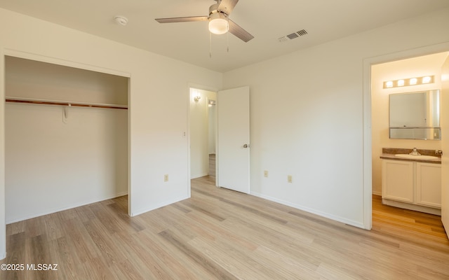 unfurnished bedroom featuring sink, light hardwood / wood-style flooring, ceiling fan, connected bathroom, and a closet