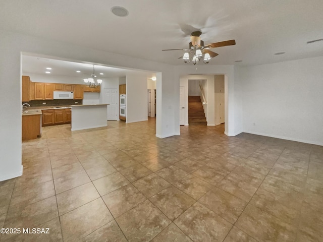 unfurnished living room with sink and ceiling fan with notable chandelier