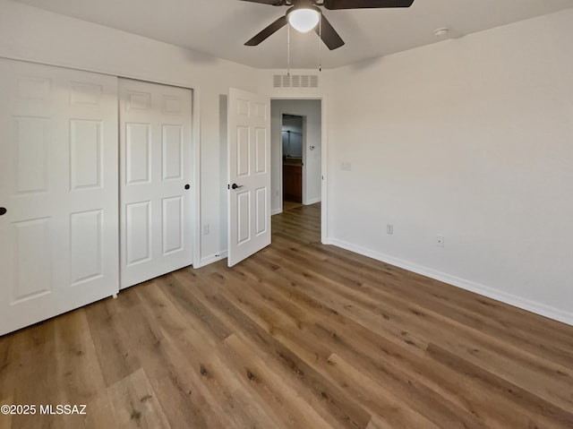 unfurnished bedroom with hardwood / wood-style flooring, ceiling fan, and a closet