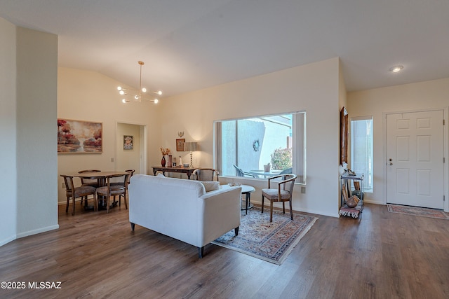 living room featuring dark wood-type flooring, vaulted ceiling, and a notable chandelier