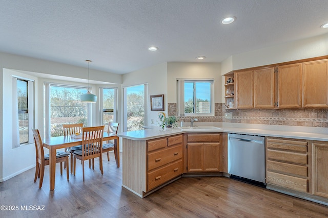 kitchen featuring sink, hanging light fixtures, kitchen peninsula, dishwasher, and decorative backsplash