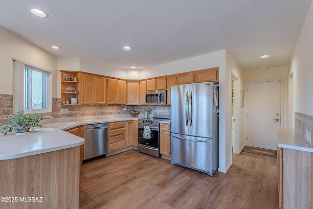 kitchen featuring sink, light hardwood / wood-style flooring, a textured ceiling, stainless steel appliances, and decorative backsplash