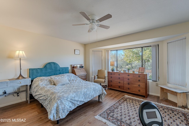 bedroom with hardwood / wood-style flooring, ceiling fan, and a textured ceiling