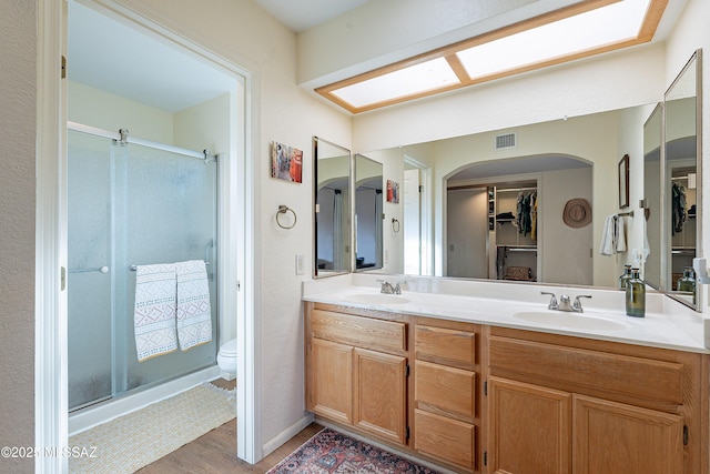 bathroom featuring walk in shower, vanity, toilet, and hardwood / wood-style floors