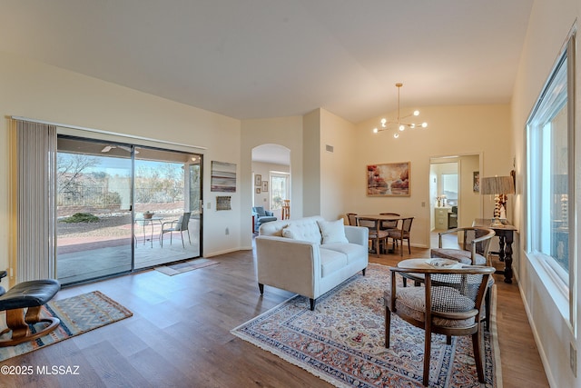 living room with wood-type flooring, plenty of natural light, a notable chandelier, and high vaulted ceiling